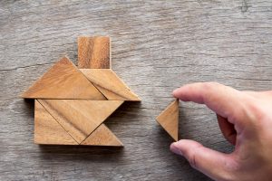 Person places wooden triangle piece in among puzzle